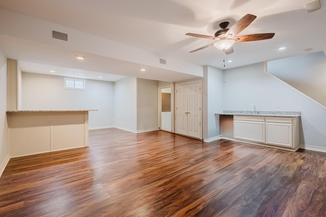 interior space with bar area, baseboards, wood finished floors, and a ceiling fan