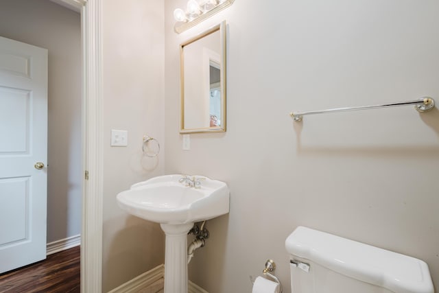 half bath featuring toilet, wood finished floors, and baseboards