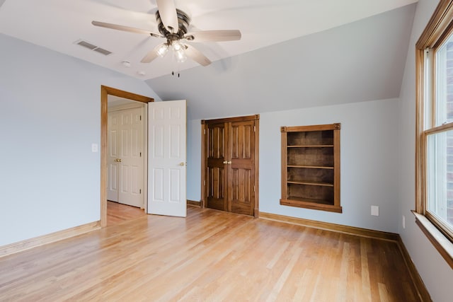 unfurnished bedroom with lofted ceiling, multiple windows, visible vents, and light wood-style floors