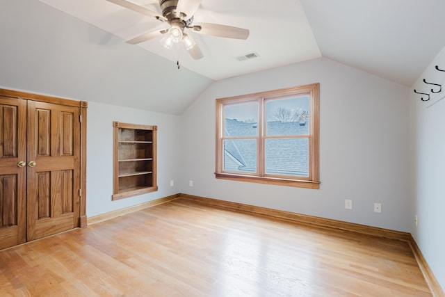 bonus room with light wood finished floors, vaulted ceiling, visible vents, and built in features