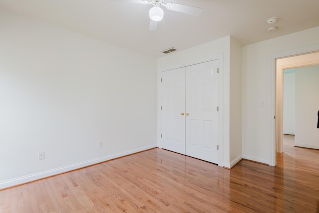 unfurnished bedroom featuring wood finished floors, a closet, ceiling fan, baseboards, and visible vents