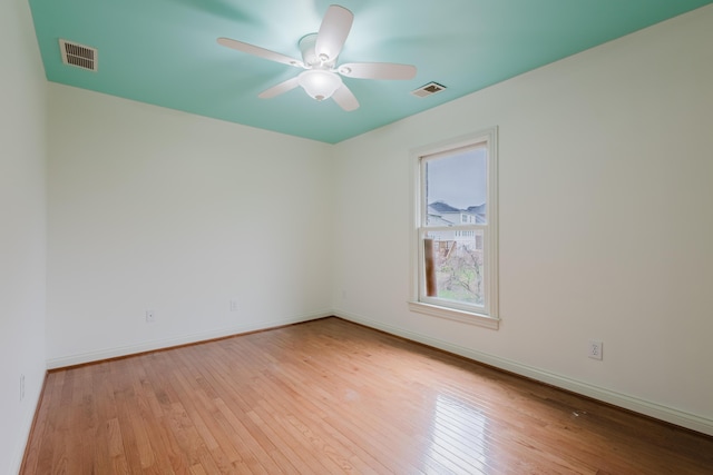 empty room with baseboards, visible vents, ceiling fan, and light wood finished floors
