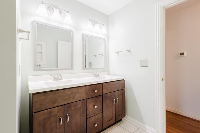 bathroom featuring double vanity, a sink, and baseboards