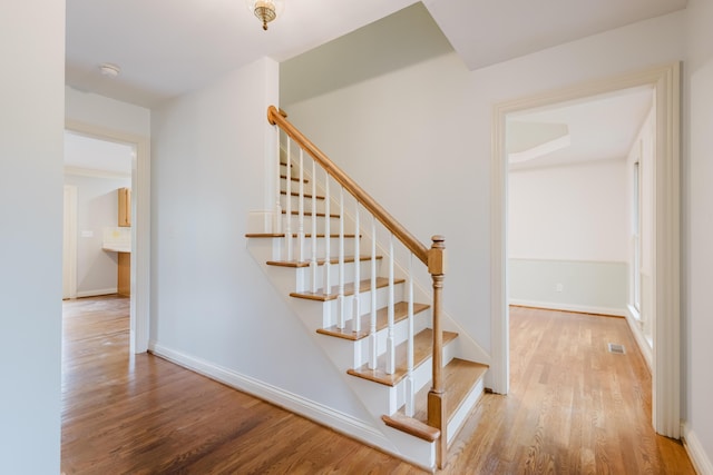 stairs with baseboards, visible vents, and wood finished floors