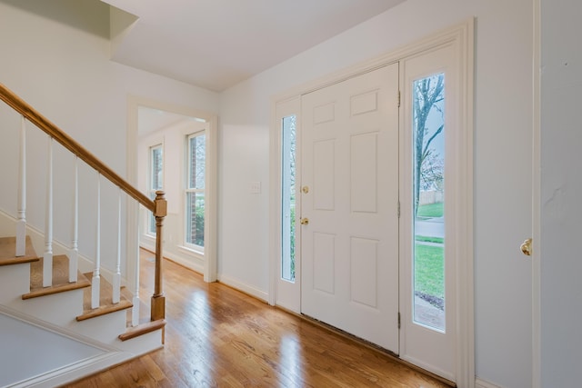 foyer featuring wood finished floors, baseboards, and stairs