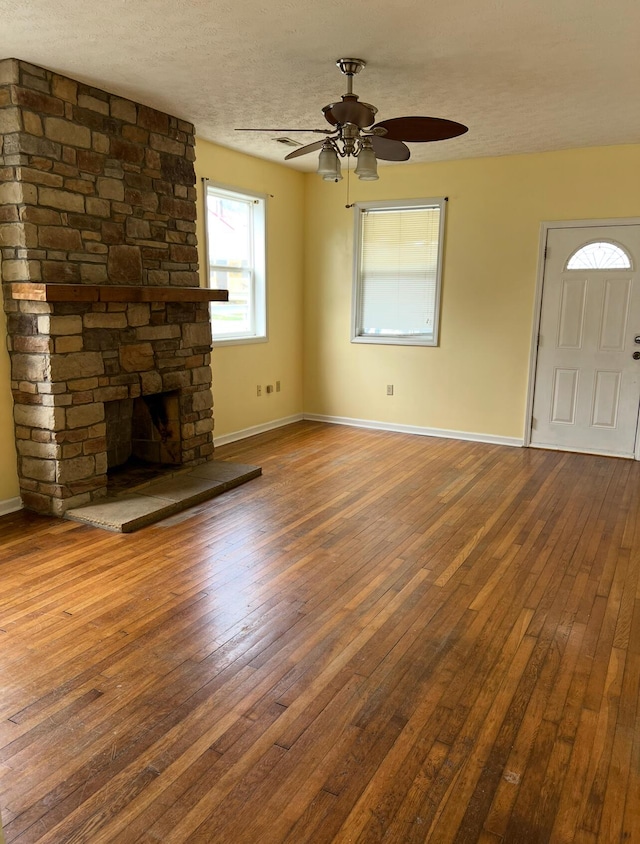 115 Georgia St, Winchester, KY 40391 - unfurnished living room with baseboards, a stone fireplace, a textured ceiling, ceiling fan, and hardwood / wood-style flooring