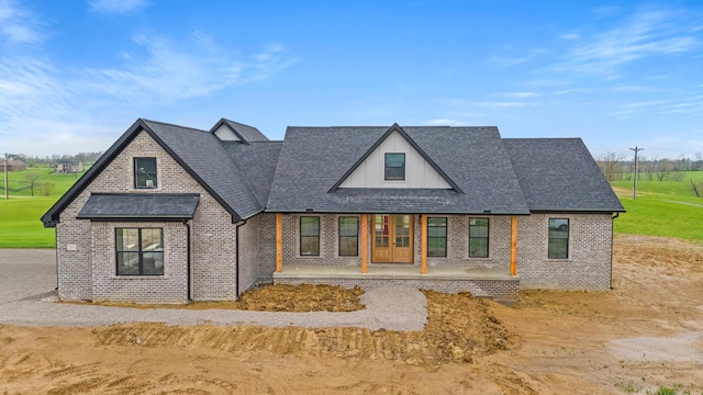 view of front of property with a shingled roof and brick siding