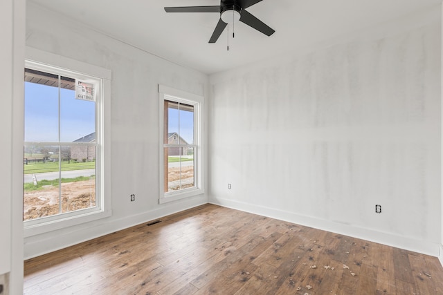 unfurnished room with baseboards, ceiling fan, wood-type flooring, and visible vents