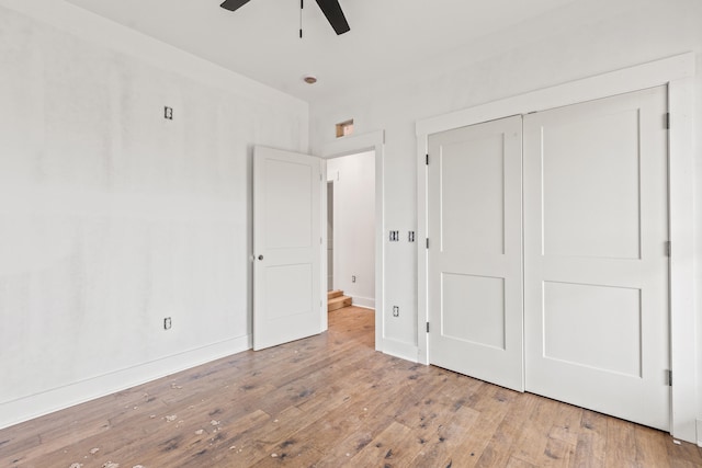 unfurnished bedroom featuring baseboards, a closet, hardwood / wood-style floors, and ceiling fan
