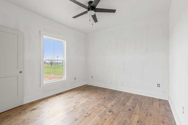spare room with hardwood / wood-style floors, a ceiling fan, baseboards, and visible vents