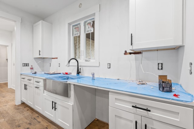 kitchen with light countertops, a sink, and white cabinetry