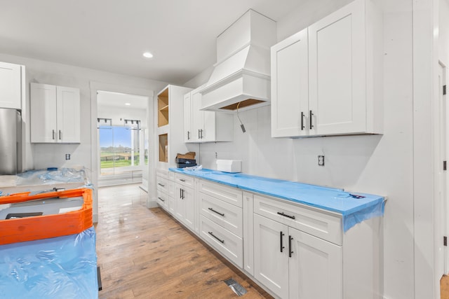 kitchen featuring light countertops, white cabinetry, and custom range hood