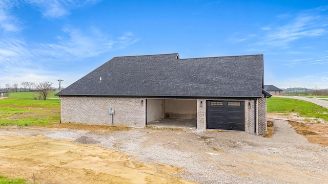 view of property exterior with a shingled roof, a garage, and brick siding