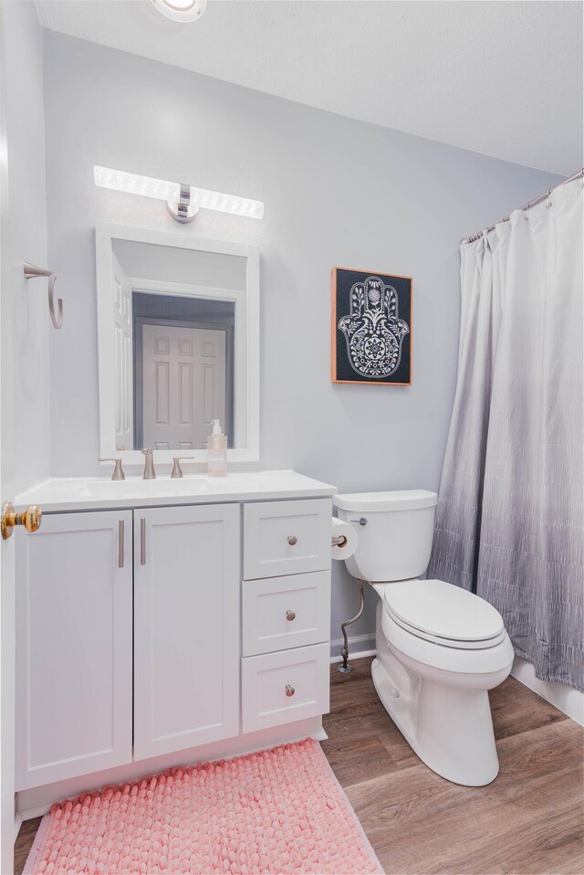 full bathroom featuring toilet, wood finished floors, vanity, and baseboards