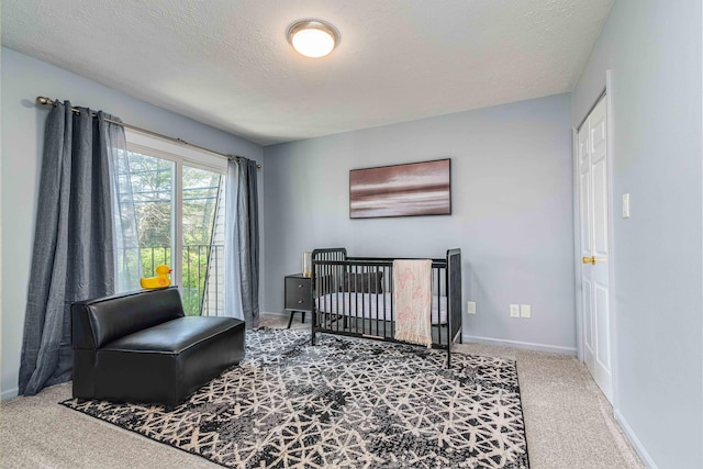 bedroom with a textured ceiling, baseboards, carpet, and a nursery area
