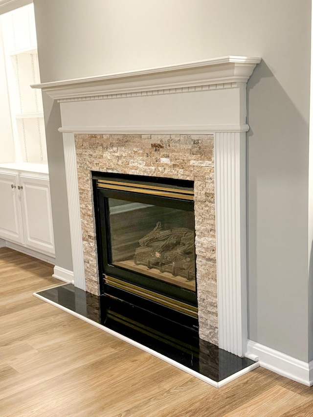 interior details with a glass covered fireplace, wood finished floors, and baseboards