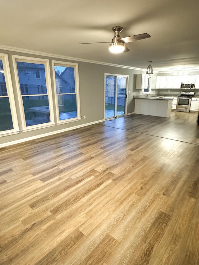 unfurnished living room featuring a ceiling fan, crown molding, and wood finished floors