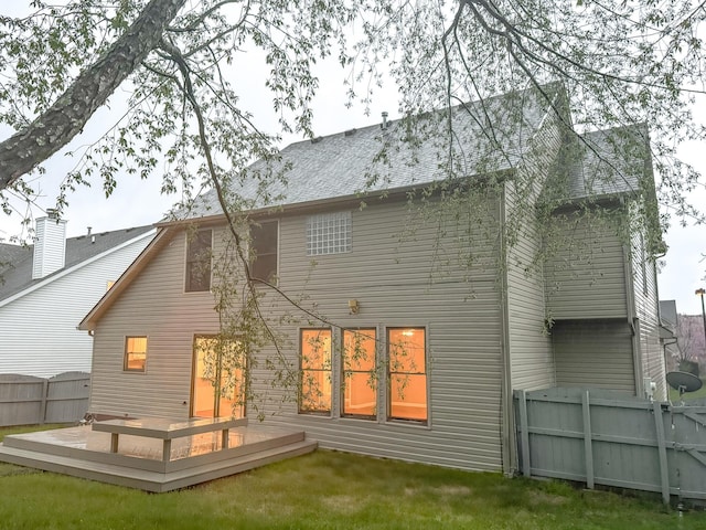 rear view of house with a wooden deck, fence, and roof with shingles