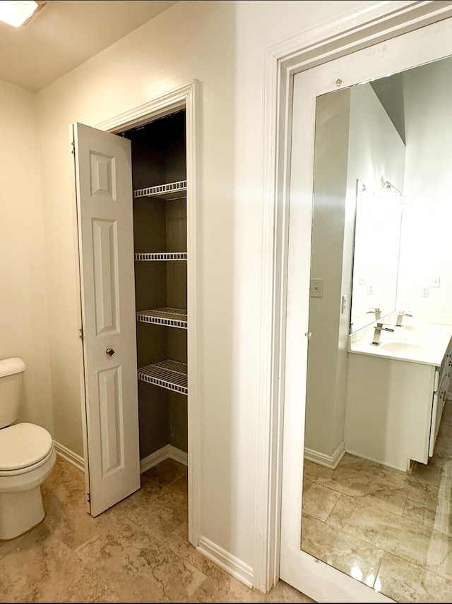 bathroom featuring baseboards, toilet, and vanity