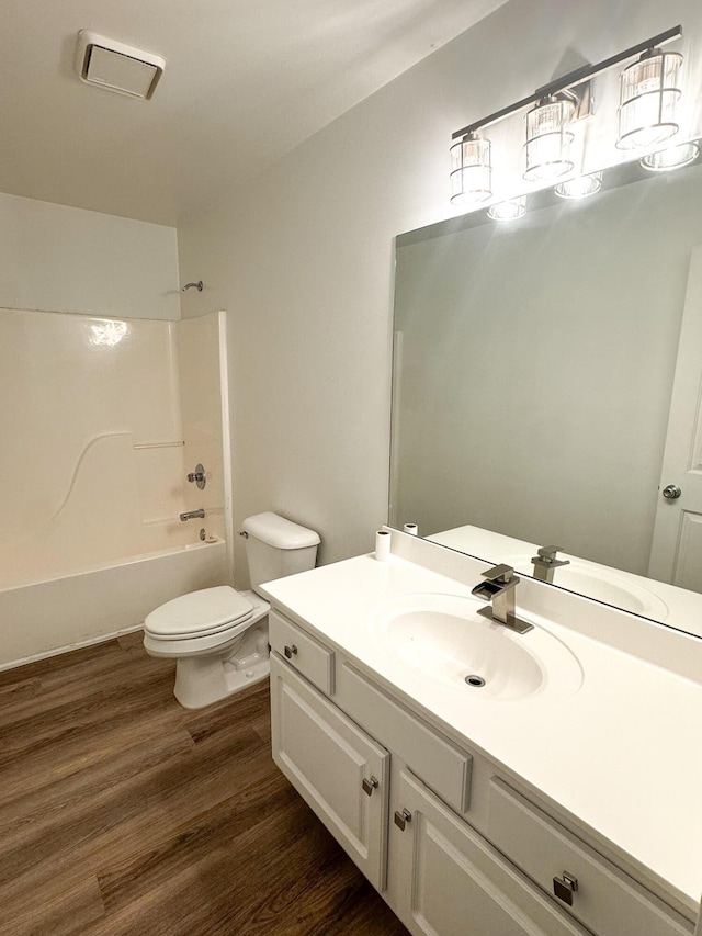 full bathroom with toilet, bathtub / shower combination, visible vents, wood finished floors, and vanity