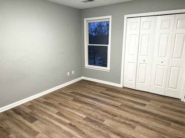 unfurnished bedroom with visible vents, baseboards, a closet, and dark wood finished floors
