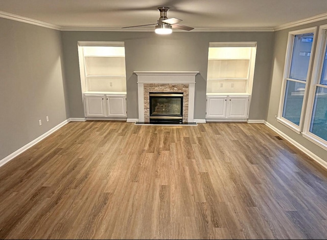 unfurnished living room with baseboards, built in features, ceiling fan, and crown molding