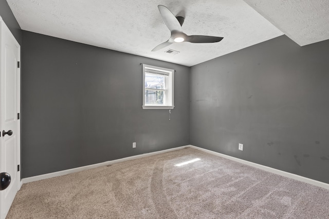 carpeted spare room featuring a textured ceiling, a ceiling fan, visible vents, and baseboards