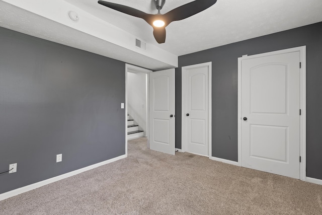 unfurnished bedroom with carpet flooring, a ceiling fan, visible vents, and baseboards