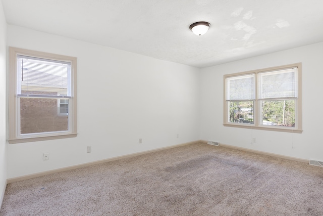 carpeted spare room featuring baseboards and visible vents