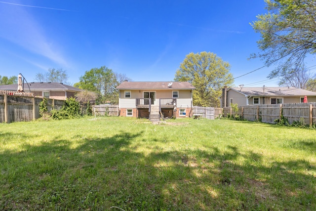 back of property with a deck, a fenced backyard, a lawn, and stairs