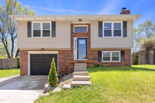 bi-level home with a front yard, driveway, a garage, and fence