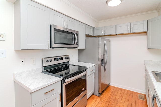 406 Kenway St, Berea, KY 40403 - kitchen featuring crown molding, light wood-type flooring, light countertops, appliances with stainless steel finishes, and visible vents