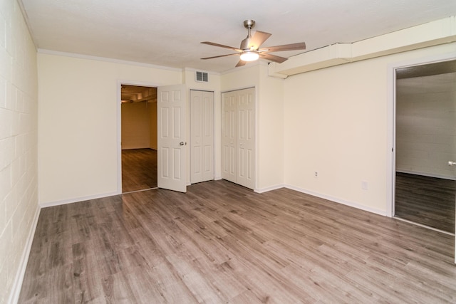 406 Kenway St, Berea, KY 40403 - unfurnished bedroom featuring baseboards, visible vents, a ceiling fan, wood finished floors, and two closets