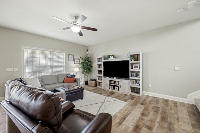 living area featuring baseboards, a ceiling fan, and wood finished floors