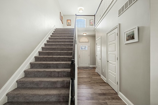 stairway with wood finished floors, baseboards, and visible vents