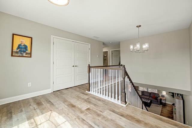 empty room featuring baseboards, an inviting chandelier, and wood finished floors