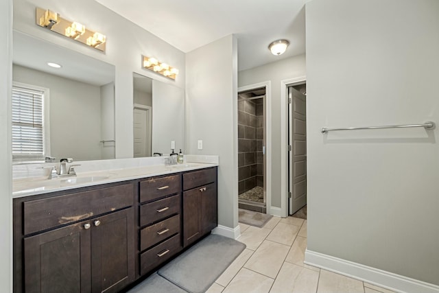 full bathroom featuring a shower stall, double vanity, a sink, and baseboards