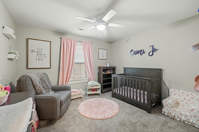 carpeted bedroom featuring a crib, visible vents, and a ceiling fan