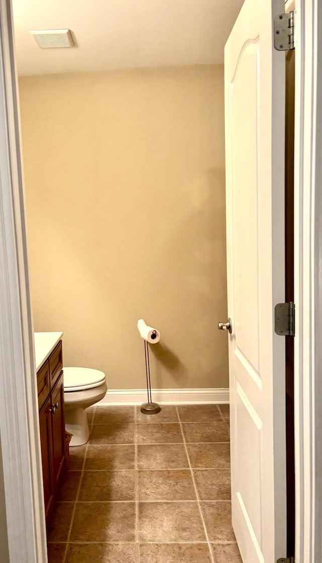 bathroom featuring vanity, baseboards, visible vents, and toilet