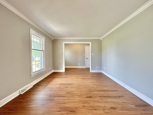 spare room featuring wood finished floors, ornamental molding, and visible vents