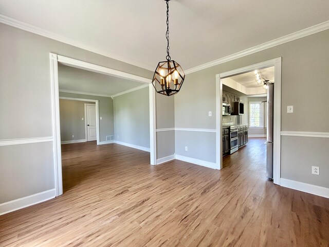 unfurnished dining area featuring baseboards, light wood-type flooring, an inviting chandelier, and ornamental molding
