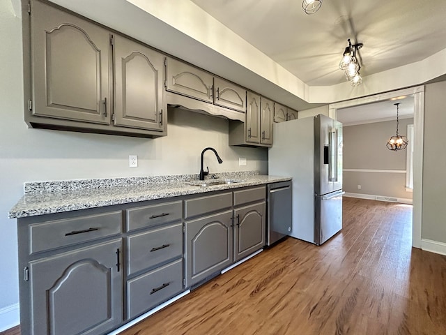 kitchen featuring stainless steel appliances, dark wood finished floors, a sink, and gray cabinets