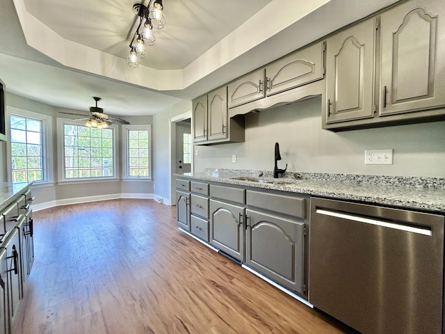 kitchen with baseboards, a sink, light wood-style floors, gray cabinetry, and stainless steel dishwasher