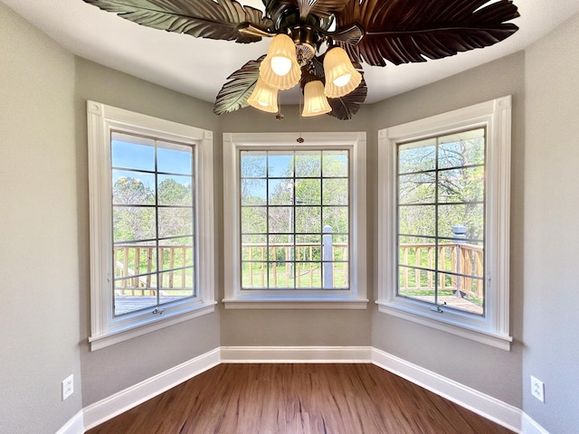 spare room featuring dark wood-type flooring, baseboards, and a wealth of natural light