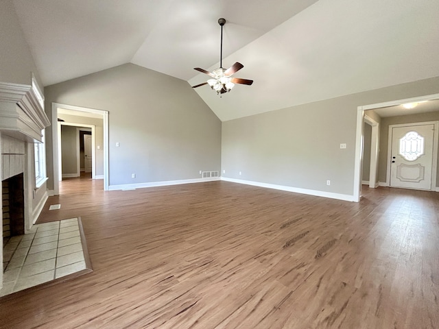 unfurnished living room with ceiling fan, a fireplace, wood finished floors, lofted ceiling, and baseboards