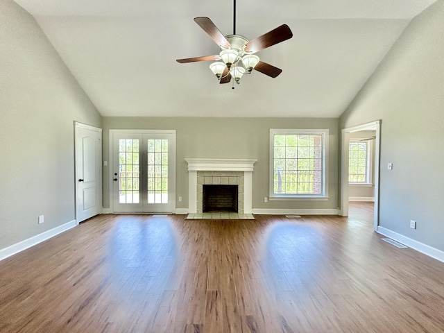 unfurnished living room with baseboards, wood finished floors, plenty of natural light, and a tile fireplace