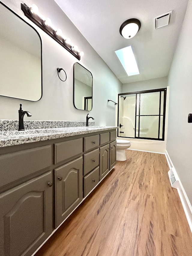 bathroom with toilet, visible vents, a skylight, a sink, and wood finished floors