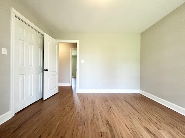 unfurnished bedroom featuring a closet, baseboards, and wood finished floors