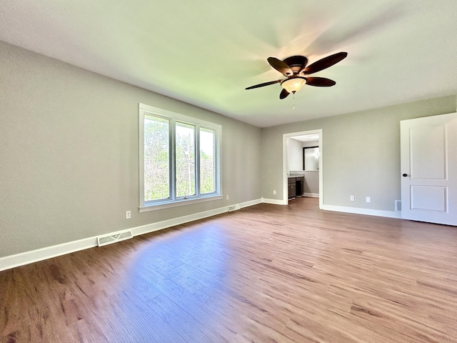interior space featuring wood finished floors, ceiling fan, baseboards, and visible vents