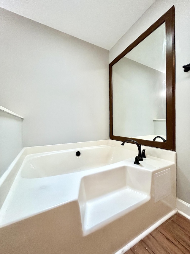 bathroom featuring a bathtub, baseboards, and wood finished floors